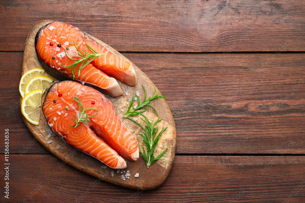 Fresh raw salmon steaks with spices, lemon and rosemary on wooden table, top view. Space for text Fresh raw salmon steaks with spices, lemon and rosemary on wooden table, top view. Space for text