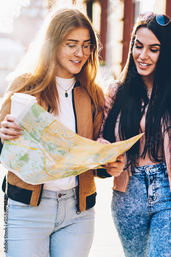 Fotografie Charming female tourists dressed in stylish casual outfit laughing and strolling