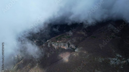 Moving Clouds Cover Mount Dajt Slope, Winter Forest with Bare Trees on Chilly Day photo