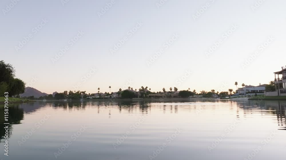 Tranquil lake in Scottsdale reflects palm trees and homes under a clear evening sky, wide shot Tranquil lake in Scottsdale reflects palm trees and homes under a clear evening sky, wide shot