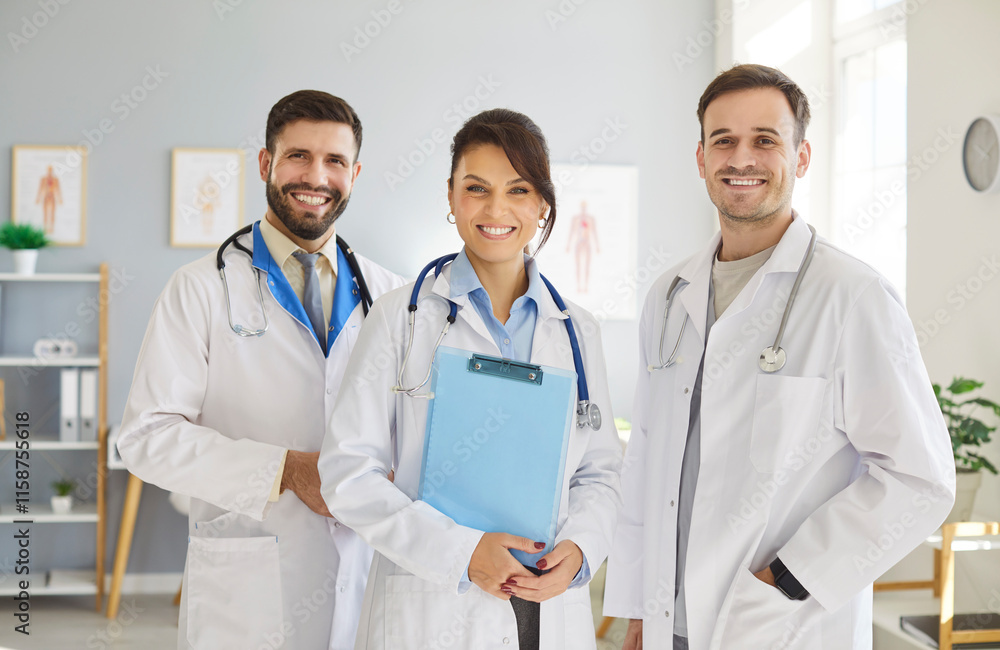 Group of happy doctors standing together in medical office, looking directly at camera. Friendly clinic staff team in white coats smiling warmly, representing teamwork and dedication to health care.