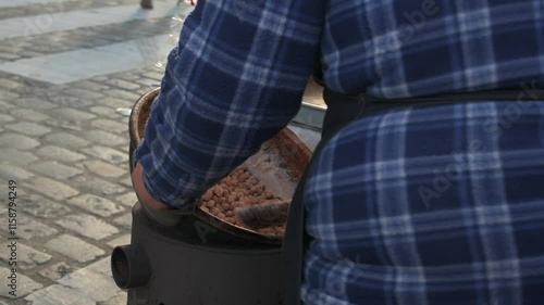 Street vendor stirring hot candied almonds in a bowl to sell at a caramelised nuts market stall in Paris, France photo