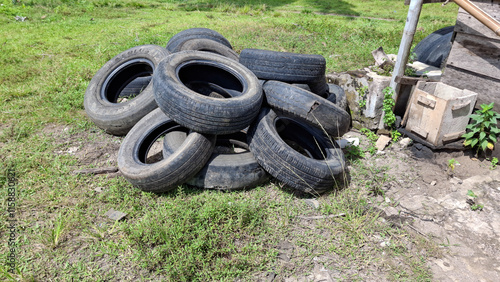 A pile of discarded tires lies abandoned in a grassy field, a stark reminder of environmental waste and the need for responsible recycling photo