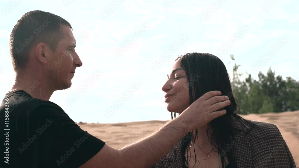 Amidst a tranquil desert area, two individuals share an intimate moment as rain falls gently around them. The atmosphere is filled with emotion and warmth despite the elements. Amidst a tranquil desert area, two individuals share an intimate moment as rain falls gently around them. The atmosphere is filled with emotion and warmth despite the elements.