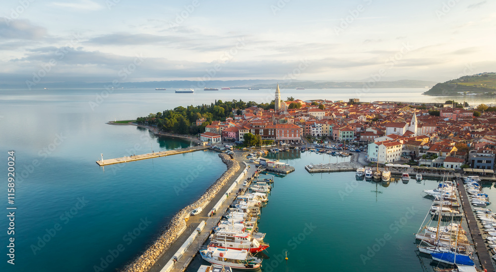 Aerial panoramic view of picturesque Izola town with the old town and buildings with red roofs, the main promenade, the marina with boats on Adriatic sea coast, Slovenia. Aerial panoramic view of picturesque Izola town with the old town and buildings with red roofs, the main promenade, the marina with boats on Adriatic sea coast, Slovenia.