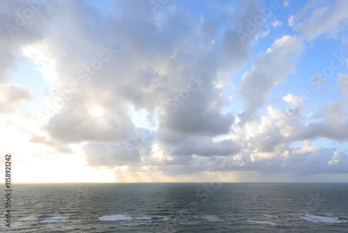 sunlight filtering through low clouds at sunset and the sea below with gentle waves, ideal as a religious concept of God photo