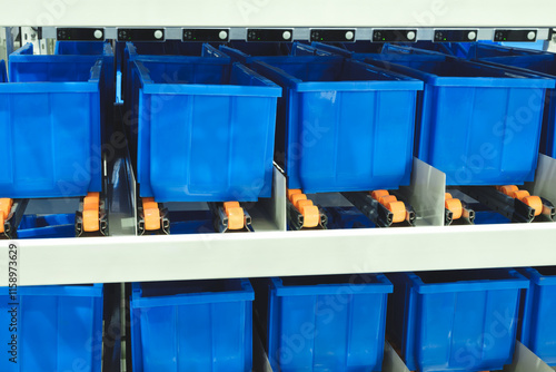 A row of blue plastic containers with orange handles are stacked on top of each other. The containers are arranged neatly and orderly. Logistics warehouse technology concept photo