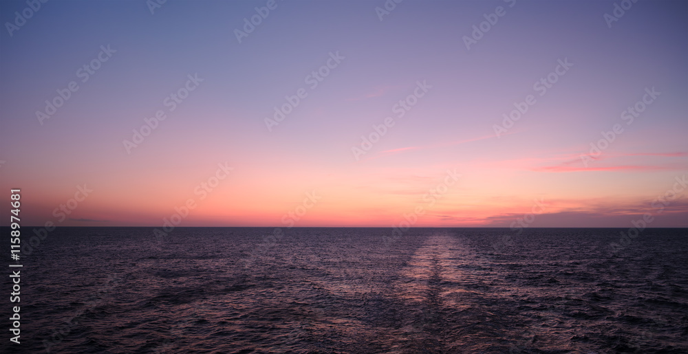 sunrise sun is setting over the ocean as beautiful backdrop for web page banner template. sky is beautiful mix of pink and purple. water is calm and still, with a cruise ship's wake off stern. sunrise sun is setting over the ocean as beautiful backdrop for web page banner template. sky is beautiful mix of pink and purple. water is calm and still, with a cruise ship's wake off stern.
