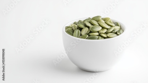 Fresh green pumpkin seeds filling a white bowl, placed on a gray background, representing healthy eating and natural ingredients