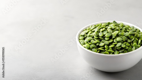 Fresh green pumpkin seeds filling a white bowl, placed on a gray background, representing healthy eating and natural ingredients