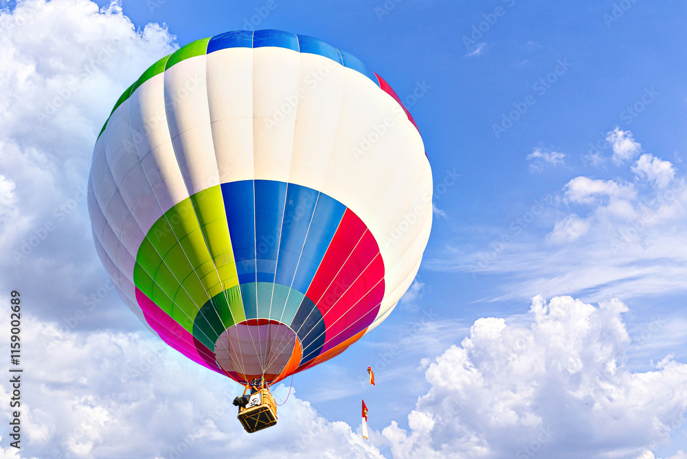 Obraz premium Colorful hot air balloon flying over blue sky with white clouds 