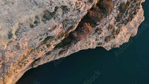 Rugged Algarve cliffs with a top-down aerial view showcasing the golden tones of the coastline at sunset. A peaceful seascape perfect for adventure and nature lovers