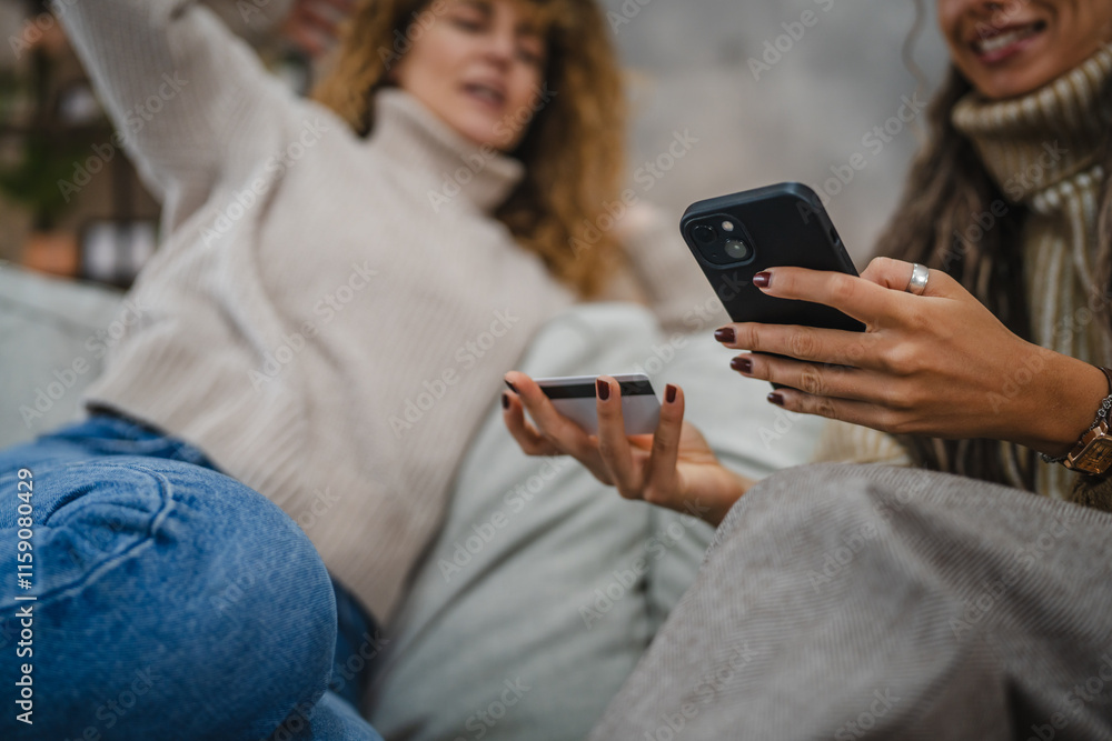 Fototapeta premium two friendly women use cellphone and credit card make payments online
