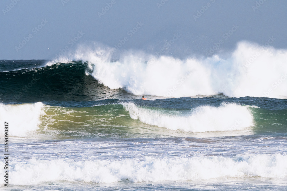 Obraz premium Powerful ocean waves crash with force, creating a dramatic display of energy and movement. The vibrant blue and white hues of the water emphasize the raw strength of nature.