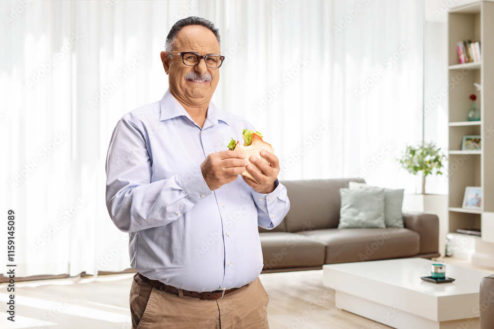 Mature man holding a sandwich and making a grimace Mature man holding a sandwich and making a grimace