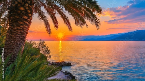 Scenic view of a silhouetted palm tree against a serene sea backdrop during a vibrant, golden sunset with soft waves reflecting the colorful sky. photo