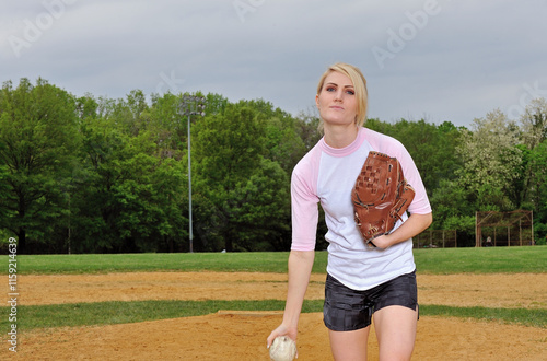 Stunning young blonde female softball player in pink and white baseball jersey shirt - pitching photo