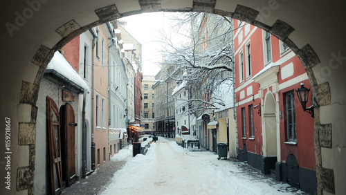 Schilderij op canvas Snowy Baltic Alley in Latvia with Colorful Houses, Cozy Medieval Decorations, an