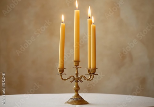 A golden candelabra with five candle sticks on it, each lit by one tall yellow wax candle, placed against an off-white tablecloth background. The candles cast a warm light and create a cozy atmosphere