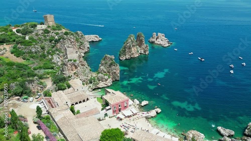 Scopello beach from above, people resting and swimming in the Tyrrhenian Sea and the fortress in the background, Sicily