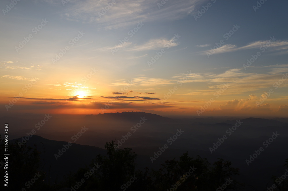 The picture depicts a sunrise on a countryside landscape with foggy mountains and clouds. The picture depicts a sunrise on a countryside landscape with foggy mountains and clouds.