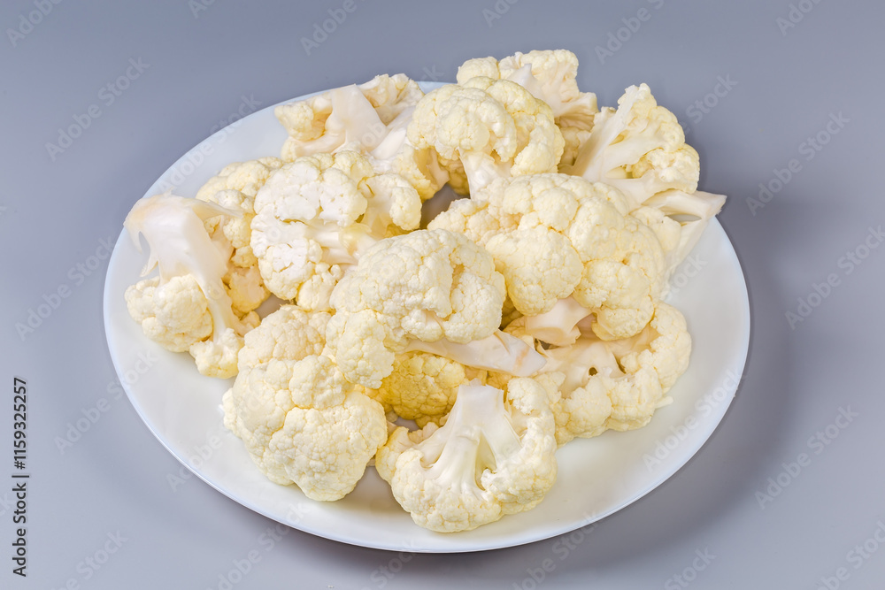 Pieces of raw cauliflower on dish on a gray background Pieces of raw cauliflower on dish on a gray background