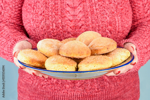 Close-up of a plate full of cottage cheese cookies in a woman's hands. photo