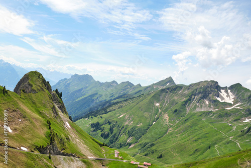 Breathtaking view of green mountains in Brienz, Switzerland, showcasing rolling hills and rugged peaks under a blue sky, perfect for nature lovers and hikers.