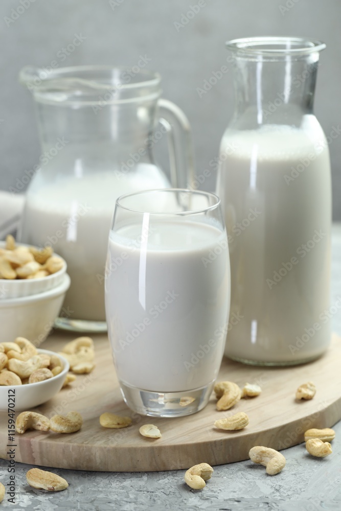 Glassware with fresh cashew milk and nuts on grey table, closeup Glassware with fresh cashew milk and nuts on grey table, closeup