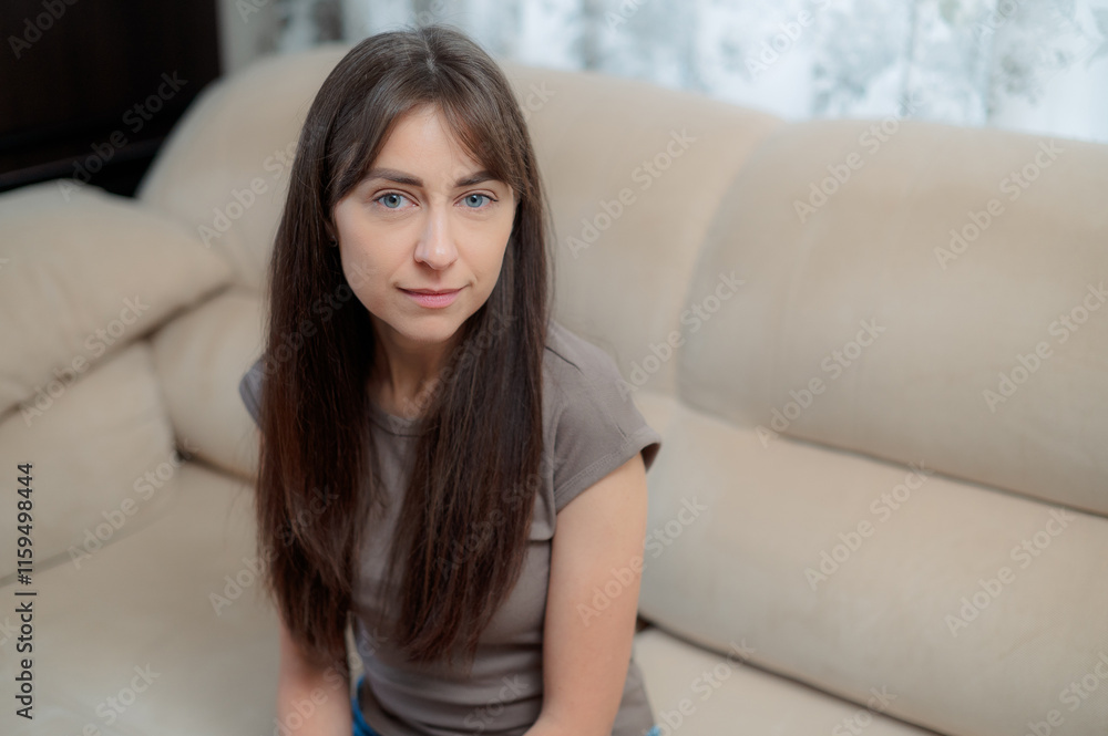 peace woman sitting comfortably on a gray couch at home, smiling and relaxing in soft natural light during the afternoon peace woman sitting comfortably on a gray couch at home, smiling and relaxing in soft natural light during the afternoon