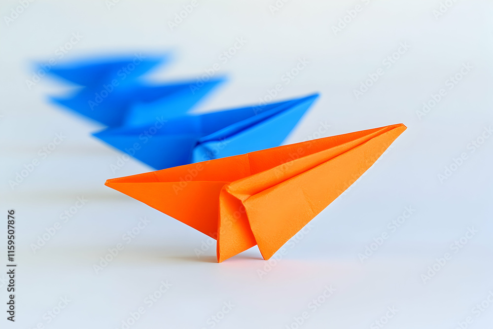 Single orange paper airplane leading a group of blue planes on a minimalist background Single orange paper airplane leading a group of blue planes on a minimalist background