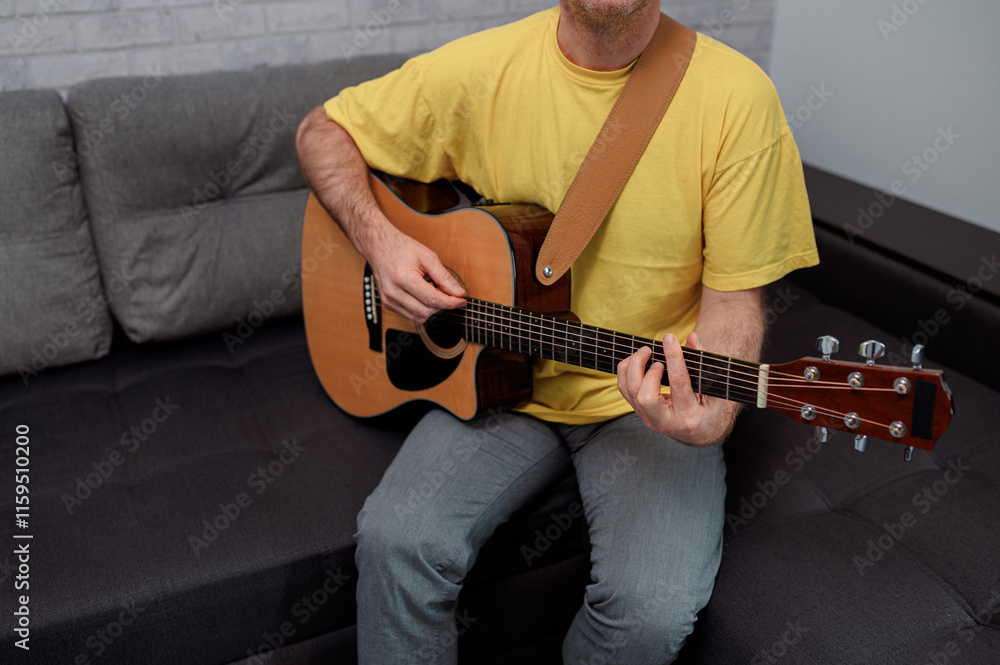Obraz premium man guitarist playing guitar at home. Relaxing and sitting on sofa