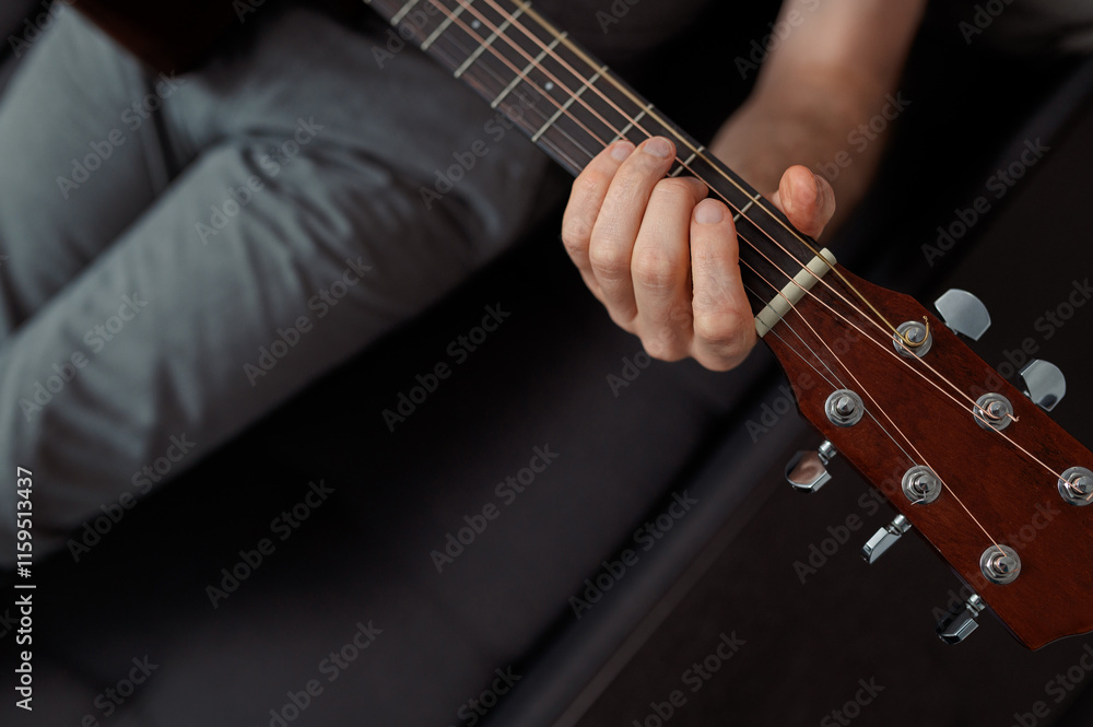 Obraz premium man guitarist playing guitar at home. Relaxing and sitting on sofa