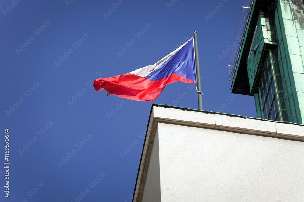 Czech national flag waving in wind with building behind, blue sky