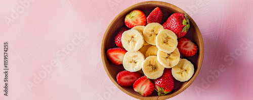 Obraz na płótnie Top-down view of a wooden bowl with sliced bananas and strawberries, wellness vibes. w salonie