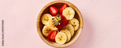 Obraz na płótnie Sliced strawberries and bananas in a wooden bowl, light pink pastel background, healthy. w salonie