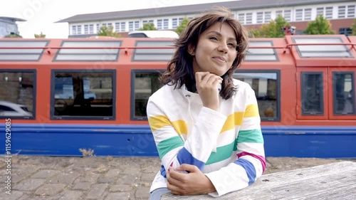 Young woman enjoys a moment of contemplation by a colorful canal boat in a vibrant urban setting photo