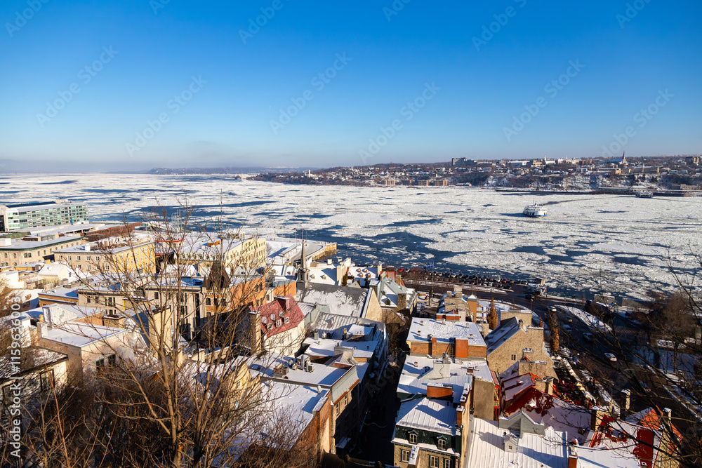 Fototapeta premium High angle view of the Petit-Champlain old town sector, with the partly frozen St. Lawrence river and the south shore seen during a sunny afternoon, Quebec City, Quebec, Canada