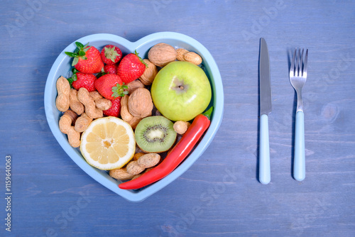 Heart shaped dish with vegetables isolated on blue wooden backgr photo