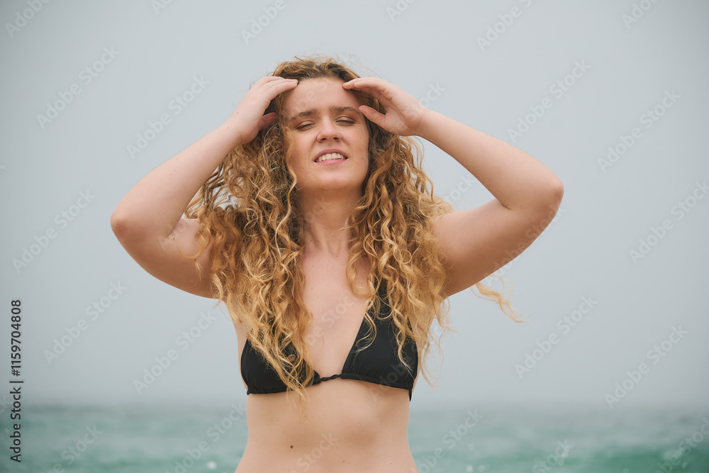 Naklejka premium Young Woman with curly hair in a Bikini by the Ocean