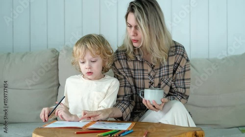 mother and son doing homework while sitting on the couch at home