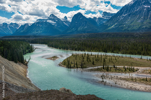 The gorgeous, aqua-colored Sunwapta River with the Canadian Rocky Mountains in the background, large puffy white clouds against a blue sky. Jasper National Park, Icefields Parkway, Alberta, Canada.
 photo