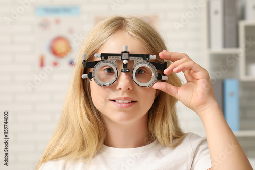 Teenage girl in trial frame at ophthalmologist's office, closeup. Children's ...
