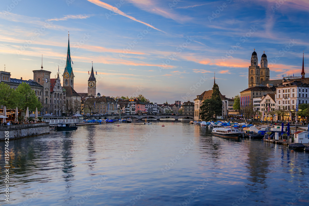 Cityscape of Zurich, Switzerland, at dusk. Buildings on the banks of the Limmat River flowing through Altstadt city center, boats along the waterfront Cityscape of Zurich, Switzerland, at dusk. Buildings on the banks of the Limmat River flowing through Altstadt city center, boats along the waterfront