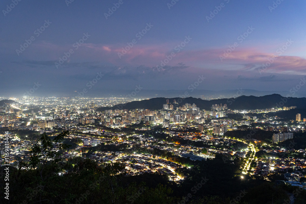 Fototapeta premium City lights illuminating Valencia, Venezuela, as seen from Casupo mountain during blue hour, creating a magical urban nightscape. Cityscape concept.