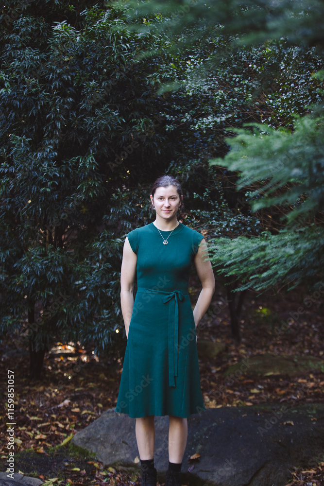 A woman stands amidst dense greenery, her confident pose and a hint of a smile blending beautifully with the vibrant natural surroundings and sunlight A woman stands amidst dense greenery, her confident pose and a hint of a smile blending beautifully with the vibrant natural surroundings and sunlight