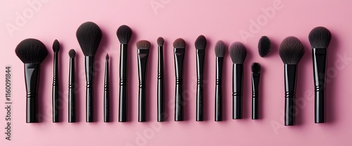 A collection of makeup brushes arranged on a pink background. photo