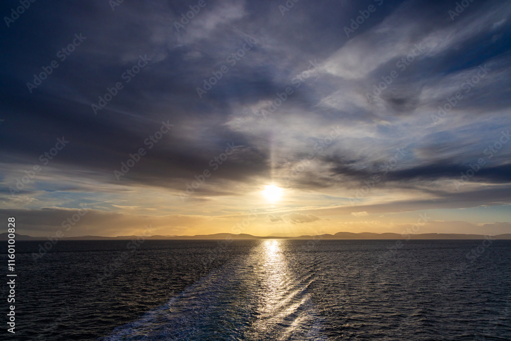 Fototapeta premium Golden Sunset Over Calm Ocean Water with Gentle Cloudy Sky