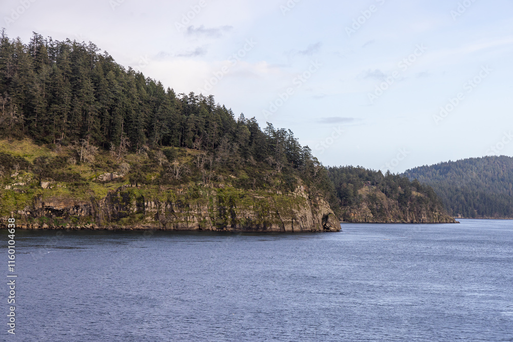 Rocky Shore and Forested Landscape Along a Calm Stretch of Water Rocky Shore and Forested Landscape Along a Calm Stretch of Water