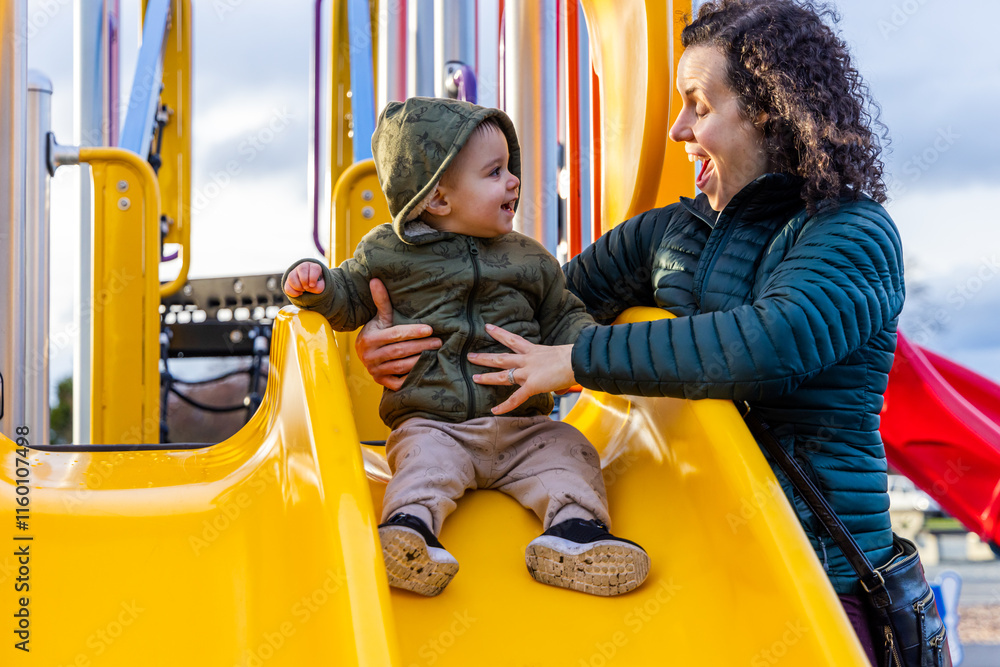 Mother and Child Bonding on a Playground Slide Outdoors Mother and Child Bonding on a Playground Slide Outdoors